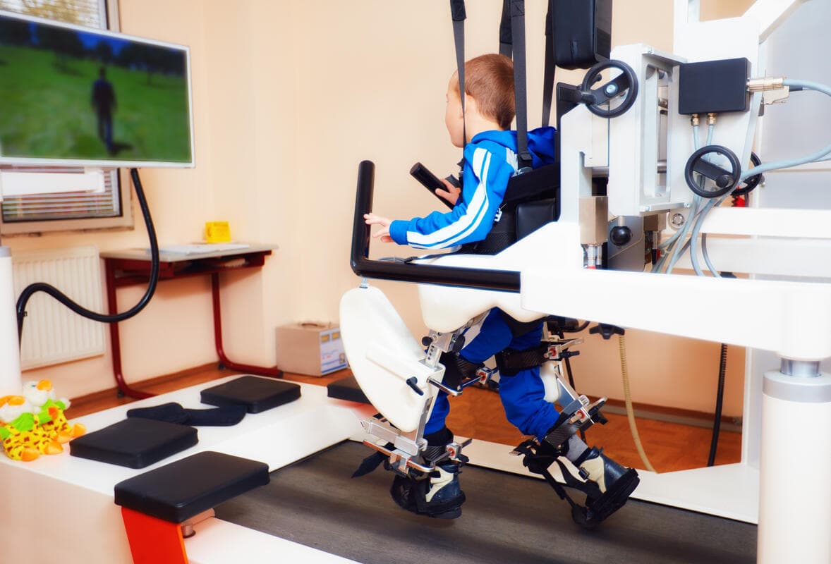Young boy using robotic gait training equipment during therapy